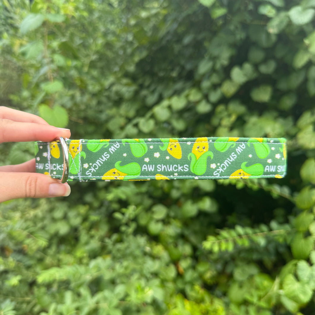 a green pet collar with a yellow and green corn Cobb that reads Aw Shucks